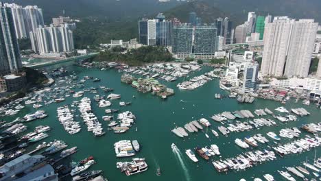 hong kong marina and typhoon shelter with the famous jumbo floating restaurant, skyscrapers and hundreds of small boats on a clear summer day, aerial pull up view.