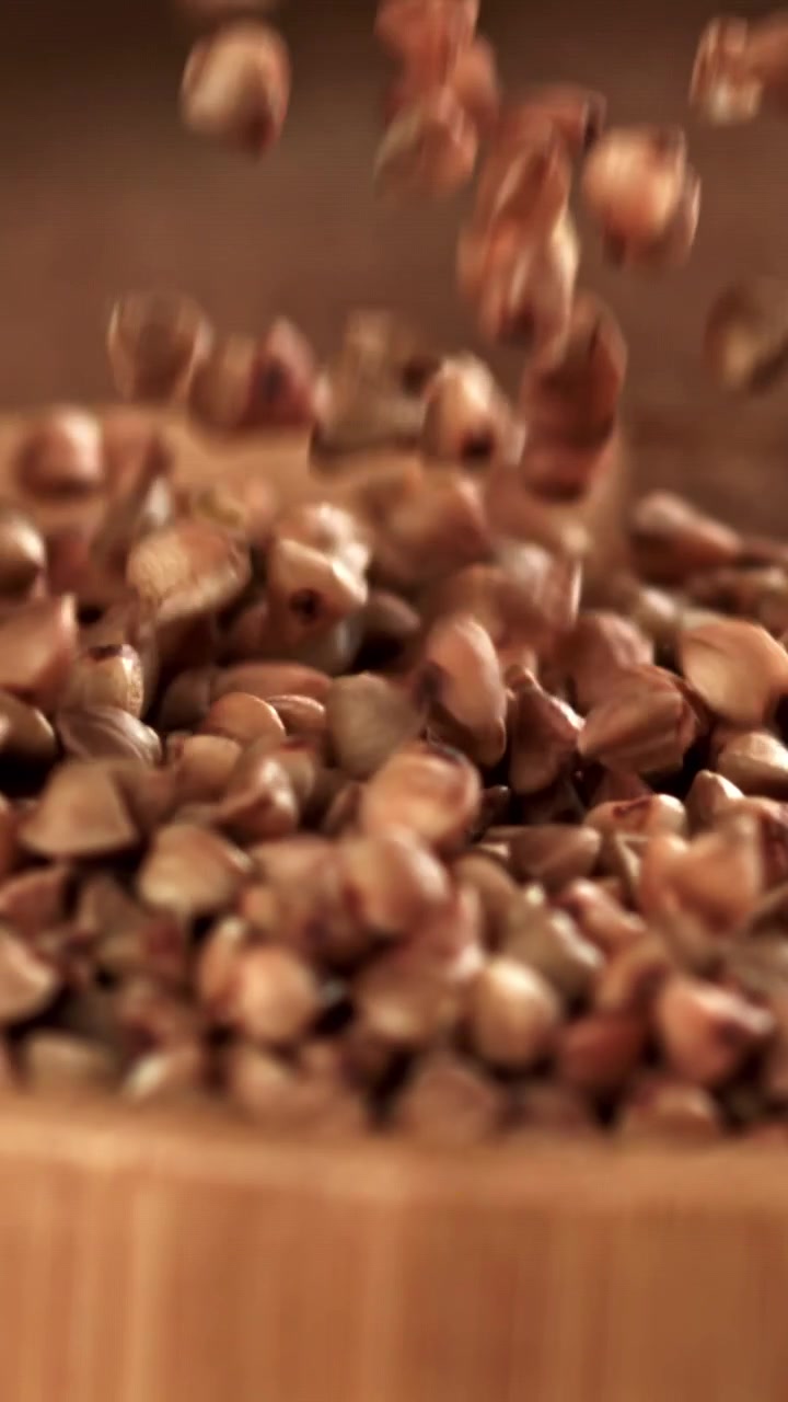 Raw Buckwheat Groats Falling Slowly into a Wooden Container