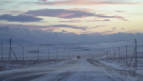 un camión conduciendo en una carretera nevada al atardecer