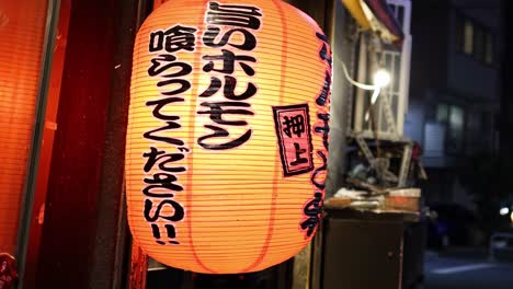 a glowing lantern with japanese characters, casting warm light in an urban setting.