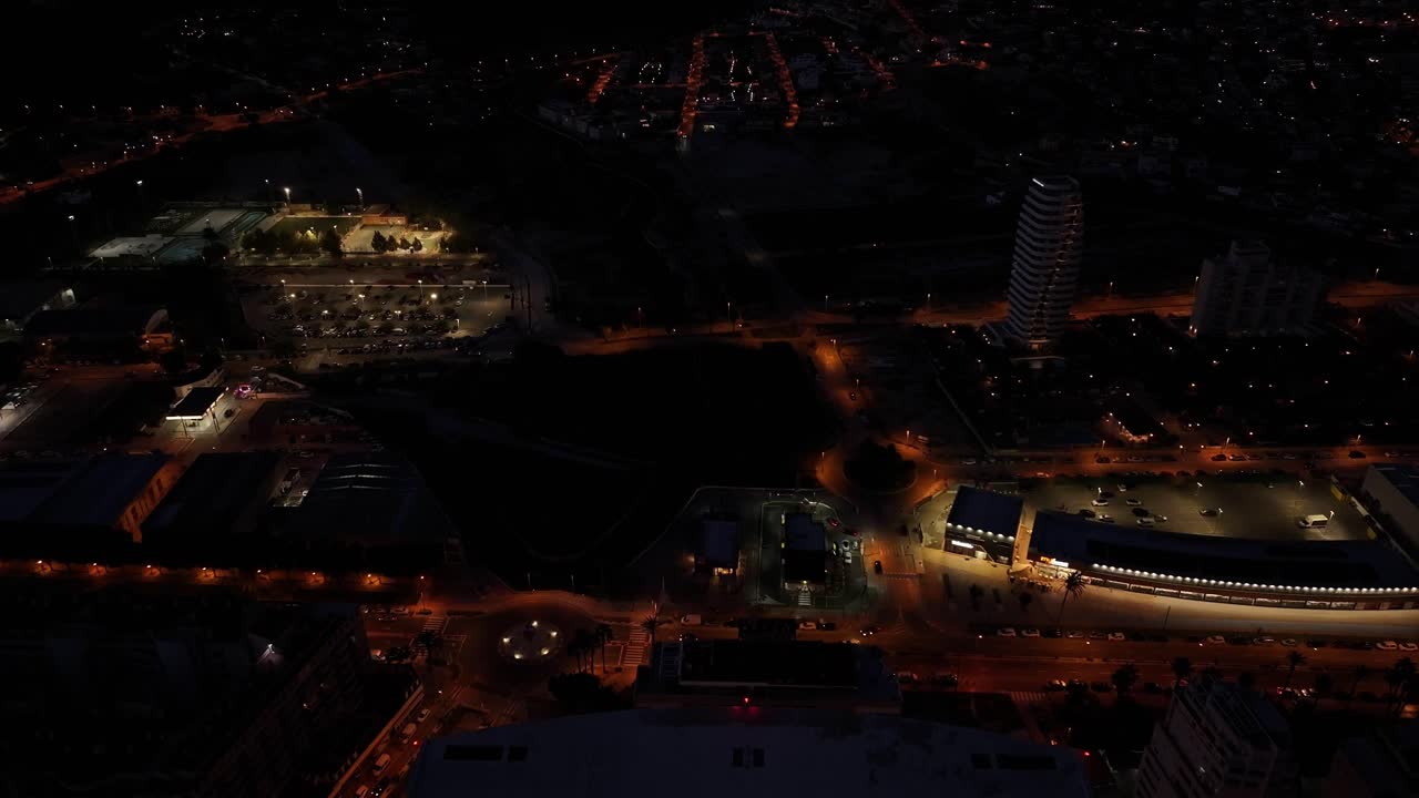 Drone glides over Estimar Hotel in Calpe at night, with glowing windows, pool lights, and the coastline illuminated under a starry sky.