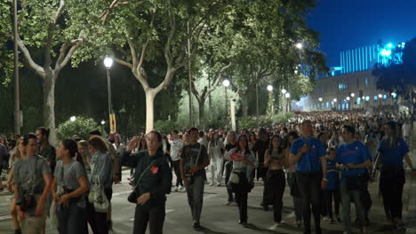 large crowd of people walking at night through a city street