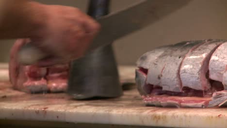 a butcher cuts fresh fish in a market