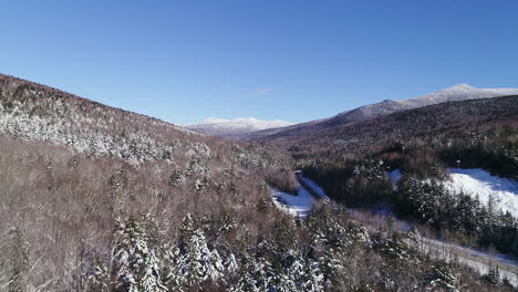 low and rising pull back drone shot of winter mountain valley with river and road