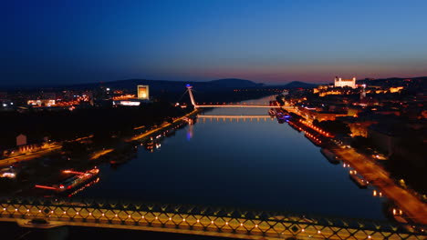 footage above the peaceful waterscape of the danube at night. lights are on at the bridges above the river. bratislava, slovakia