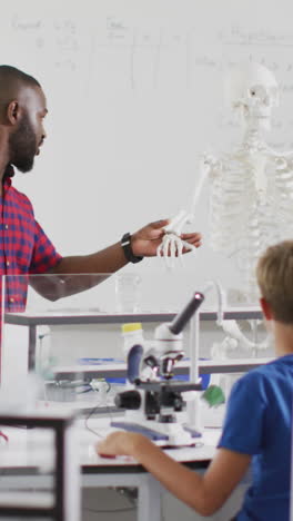 video of happy african american teacher with class of diverse pupils during anatomy lesson