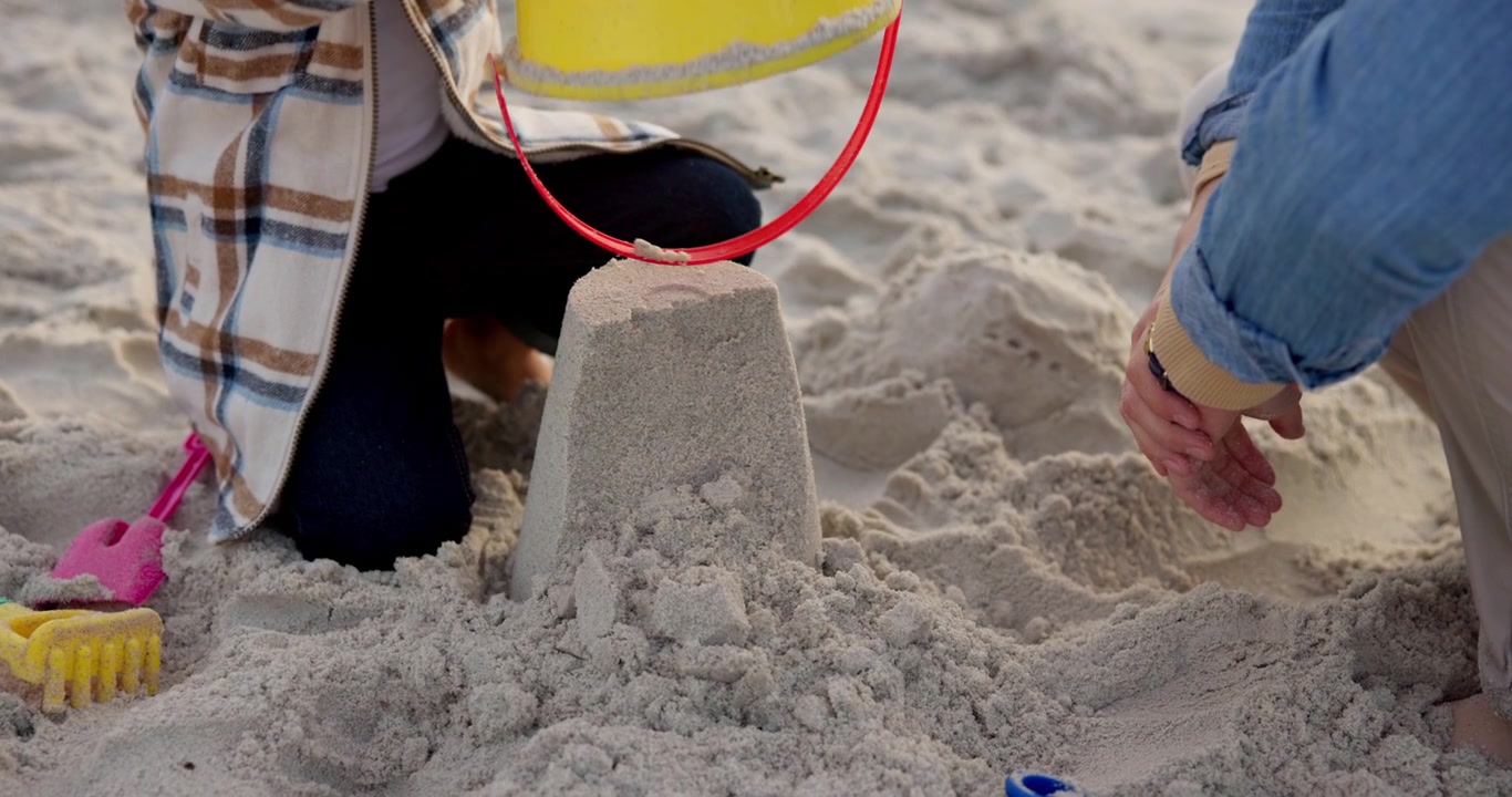 Barn och förälder bygger ett sandslott på stranden