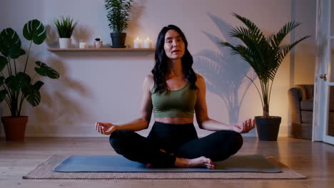 woman meditating in lotus pose at home