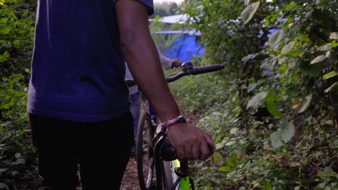 ciclista che cammina con la bicicletta nella giungla profonda cercando di scegliere il percorso nei raggi del sole rallentatore 120 mano su un sedile da vicino