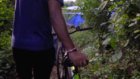 Ciclista-Caminando-Con-Bicicleta-En-La-Selva-Profunda-Buscando-El-Camino-En-Los-Rayos-Del-Sol-A-Cámara-Lenta-120-Manos-En-Un-Asiento-Cerca