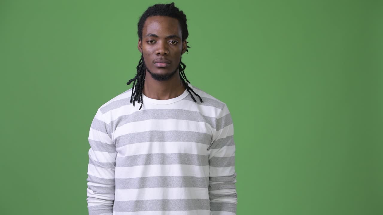 Giovane e affascinante uomo africano con i dreadlock su sfondo verde