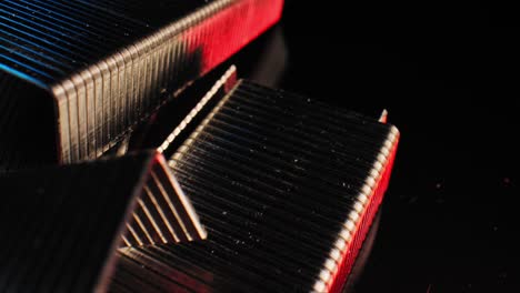 Closeup-macro-footage-scene-panning-across-a-pile-of-illuminated-staples-against-a-black-background-and-reflecting-blue-and-red-light-in-an-abstract-manner