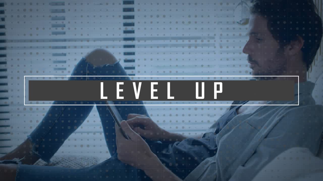 Animation of level up text banner over man using digital tablet at home