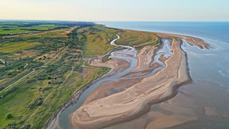 discover the idyllic charm of a golden hour coastal scene through breathtaking aerial drone footage: estuary, sandbanks, ocean, and marshlands