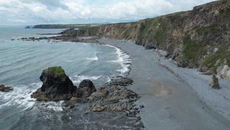 seastacks at low tide on tankardstown beach copper coast waterford ireland on a blustery summers day with storm clouds moving in