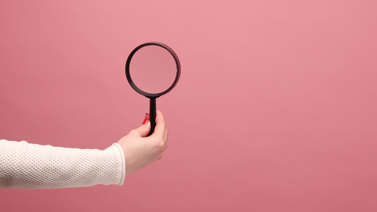 primer plano de la mano de la mujer sosteniendo una lupa, girando la lupa, inspeccionando la escena del crimen, explorando.