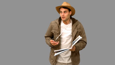 man with a map and a compass orienteering on grey screen