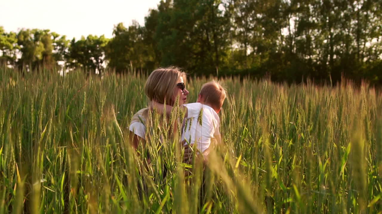 Mom hugs her son sitting in a field of wheat ears. mother's tender feelings and love