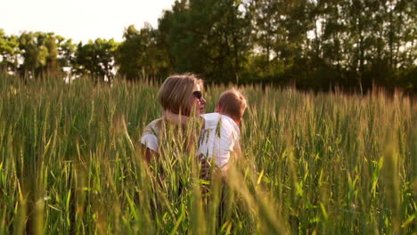 mom hugs her son sitting in a field of wheat ears. mother's tender feelings and love