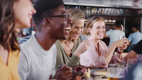 group of young friends meeting for drinks and food in restaurant