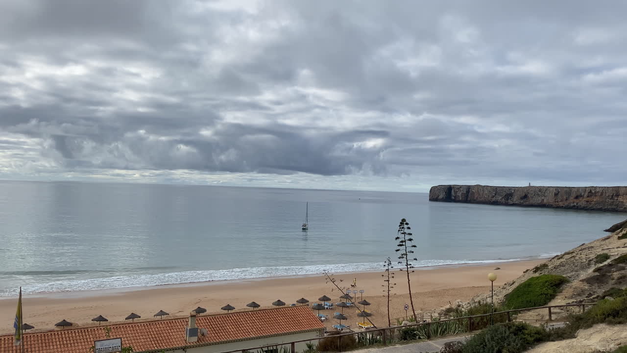 Surfers wait for waves under soft twilight light at Mareta Beach, Sagres, where peace meets energy with boats and nice light