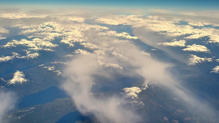Naturskønt luftfoto af sneklædte bjerge i Vancouver, dækket af skyer.