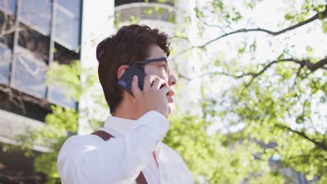 confused asian man talking on smartphone while standing on the street