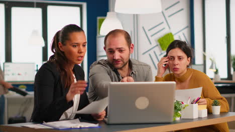 Colleagues-sitting-at-desk,-working-with-laptop-computer,-showing-first-project-results