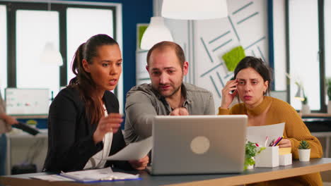 colleagues sitting at desk, working with laptop computer, showing first project results