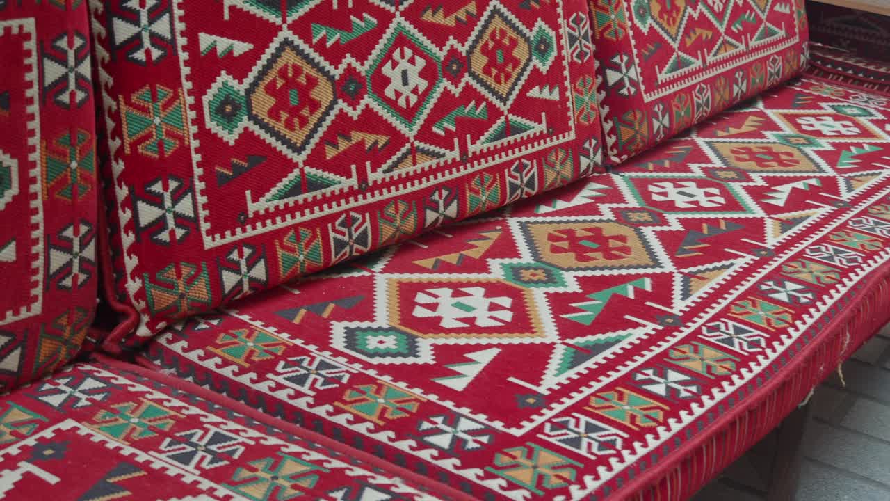 Rød sofa med puder med traditionelt geometrisk mønster