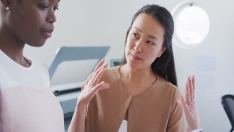 Two-diverse-businesswoman-working-and-talking-in-office