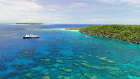 cinematic drone flight over coral reef with cruise ship anchored in fiji