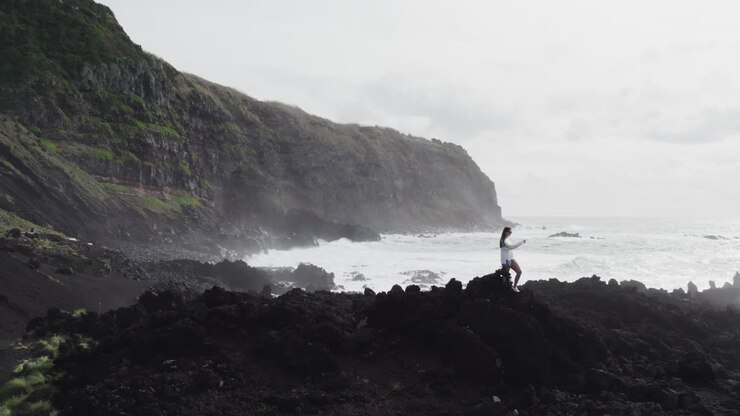 Girl tourist at Ponta da Ferraria, São Miguel Azores, overlooking ocean and cliffs