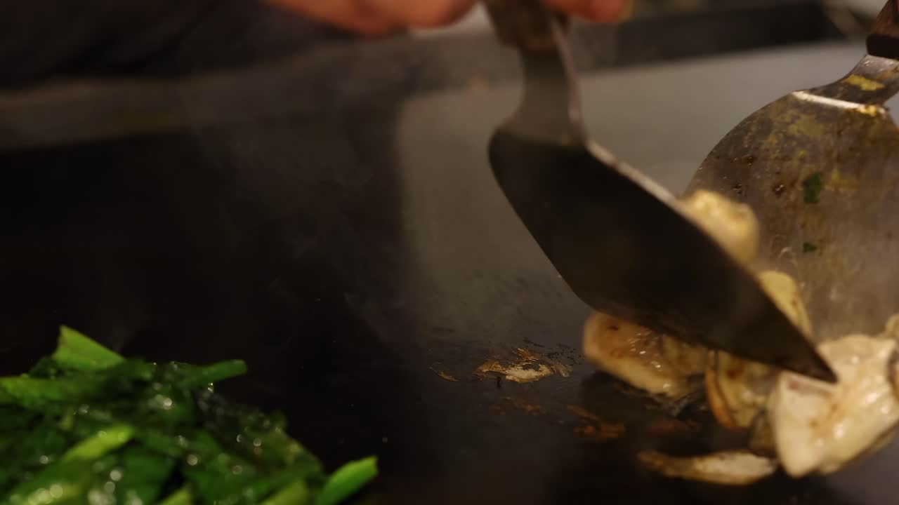 Primo Piano di Ostriche e Verdure Saltate in Padella su una Piastra Calda con una Spatola di Metallo