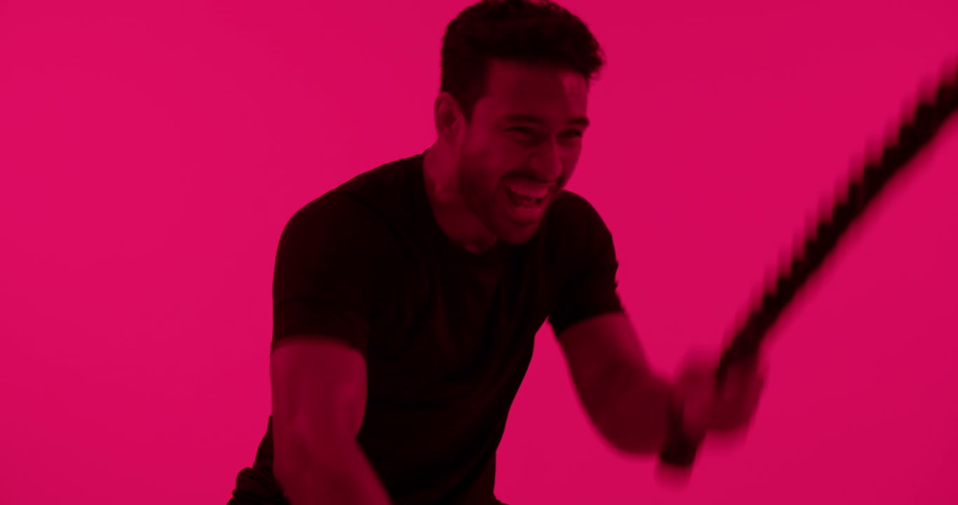 Fit Man Exercising with Battle Ropes in Red Studio