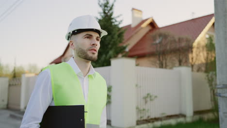 man in hard hat and safety vest holding a clipboard outdoors