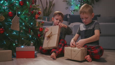 Los-Niños-Recibieron-Regalos-De-Papá-Noel-Y-Se-Agitaron-Y-Escucharon-Lo-Que-Había-Dentro-De-La-Caja-Debajo-Del-árbol-De-Navidad.-Imágenes-4k-De-Alta-Calidad