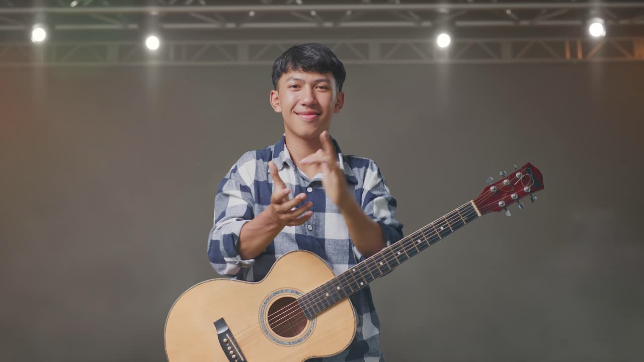 기타를 들고 무대에서 손을 치는 아시아 십대