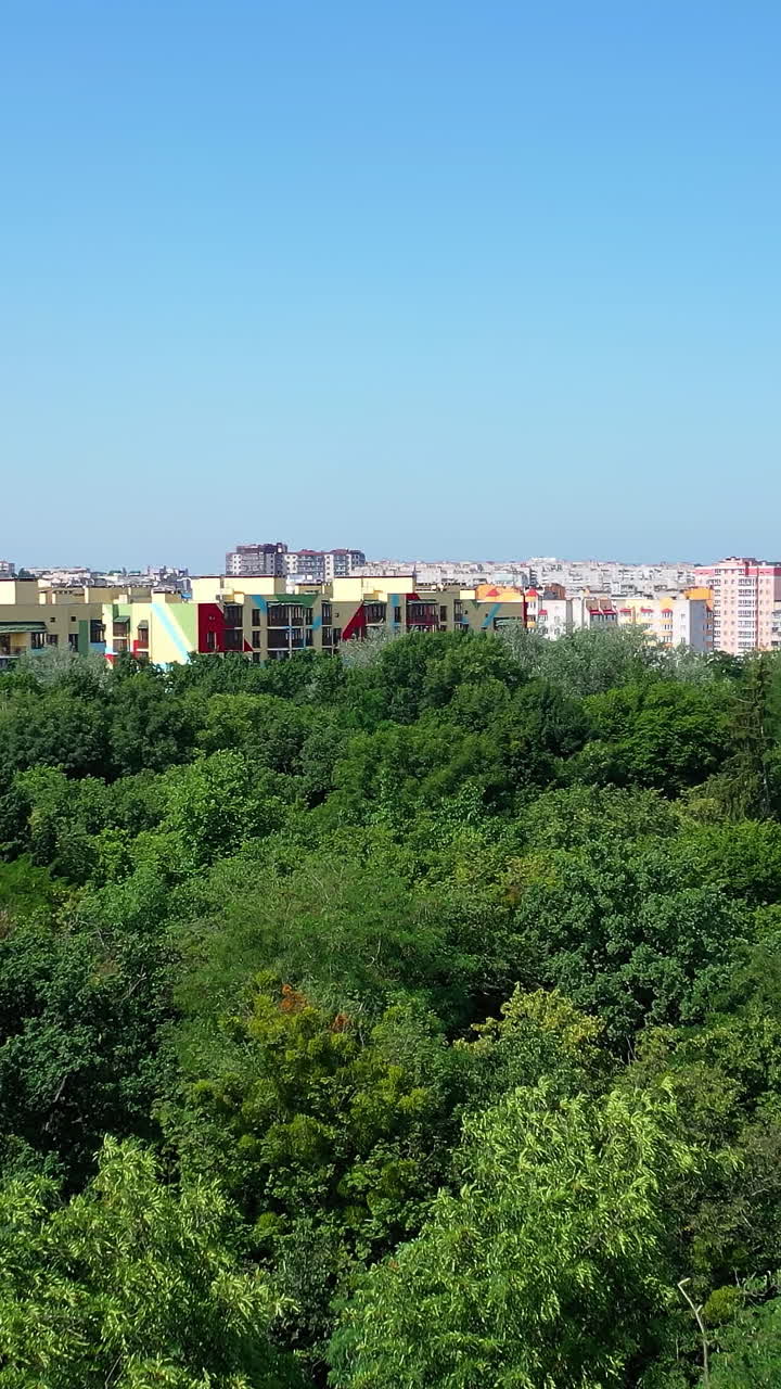 Zoom on camera view from the drone at the new apartments build in the city center. Modern urban district with architecture. Exterior of comfortable high-raised buildings Vertical video