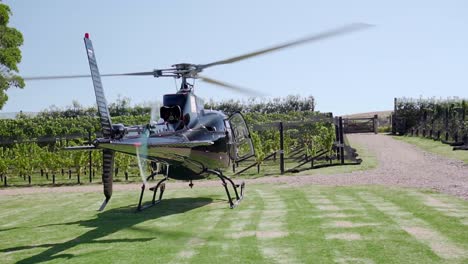 Cámara-Lenta---Helicóptero-Privado-Negro-Desde-Atrás-Listo-Para-Despegar-Del-Viñedo-En-La-Isla-Waiheke,-Nueva-Zelanda