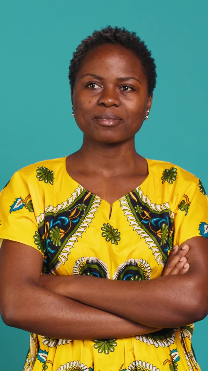 Sebejistá africká žena se zkříženýma rukama se usmívá ve studiu