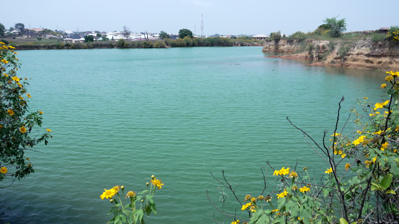 A natural dam or reservoir lake near Jos, Nigeria and wildflowers along the shoreline