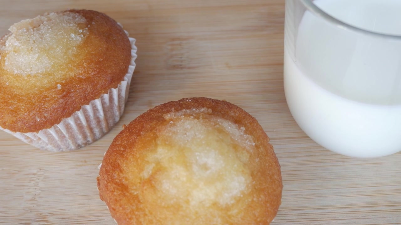 Due muffin con copertura di zucchero su una superficie di legno evocano il comfort casalingo.
