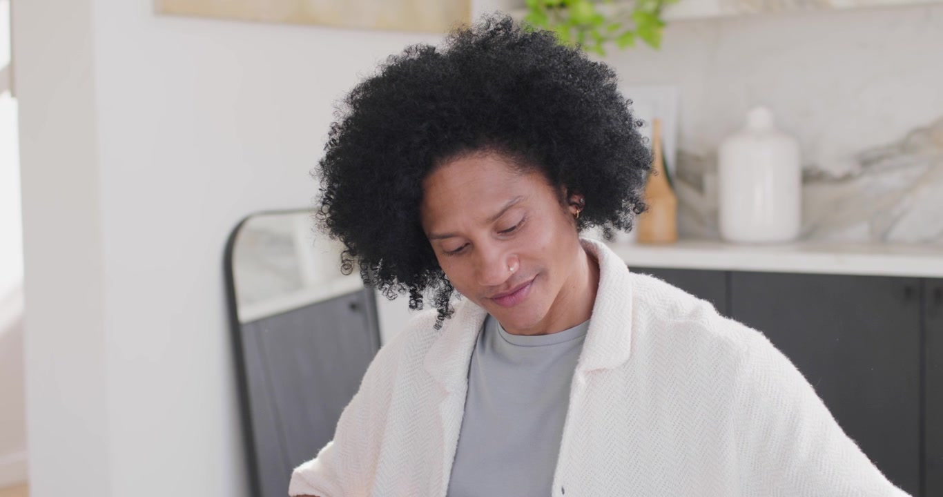 African American man starting study at home, flipping papers while checking tablet and laptop
