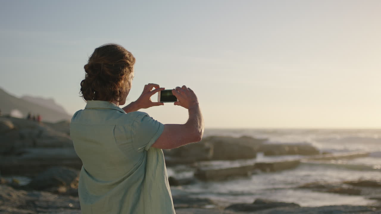 retrato de un hombre guapo tomando una foto al atardecer por la playa