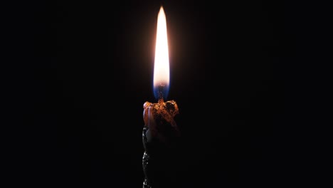 a single candle is lit on a black background. candle flame in the dark