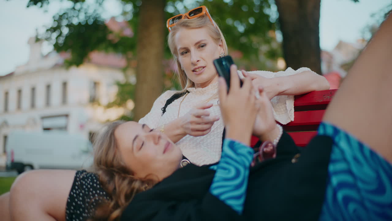 두 여자 친구 가 공원 에서 대화 를 즐기고 있다