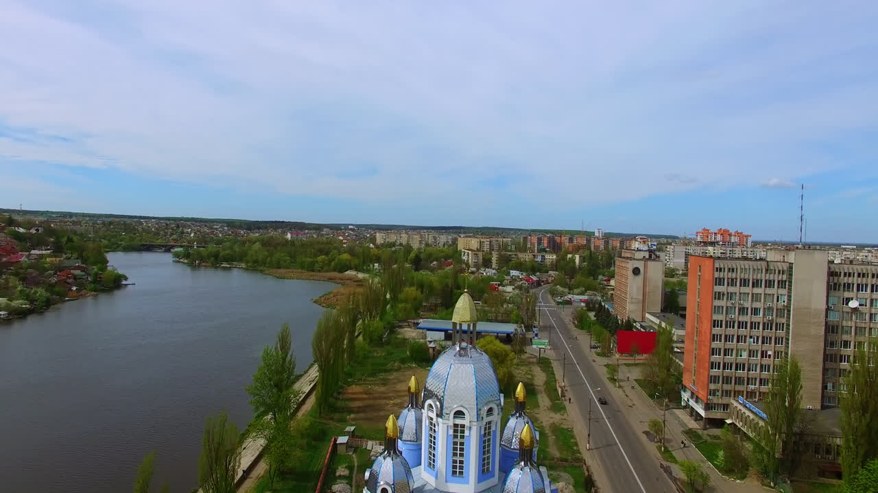 Beautiful orthodox cathedral on the picturesque riverbank. Scenery of Ukrainian city from top view.