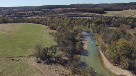 Aerial-view-following-the-river-running-before-the-freeway-on-the-horizon