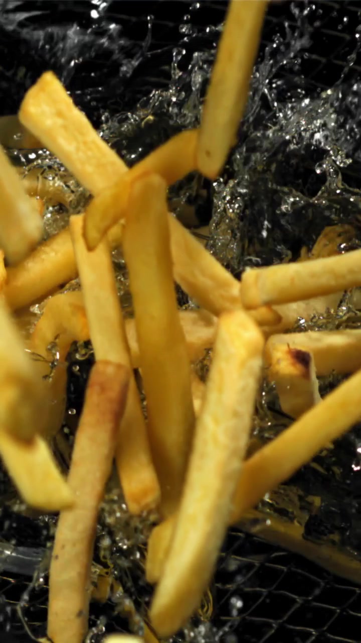 Patatine fritte in slow motion che cadono e friggono nell'olio bollente
